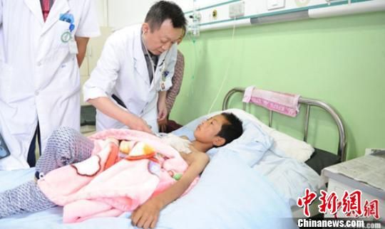 7月24日，在岷县中医院内，甘肃省人民医院专职医生正在细心查看11岁马强强的病情。地震发生后，甘肃省人民医院在灾区岷县中医院设立了灾区爱心病房，并有专职医生、专职护士负责照顾，以此来帮助在地震中受伤的群众。杨艳敏 摄 